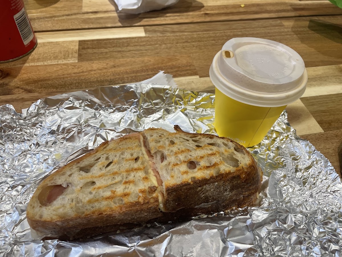 Toasted ham and cheese sandwich with a takeaway coffee